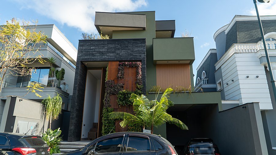 Fachada da residência: pele de pedra escura, jardim vertical e painel ripado